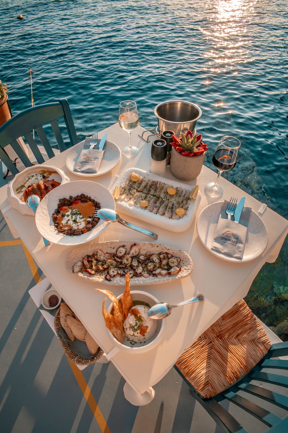 Pesce gourmet e vino serviti su un tavolo in riva al mare.